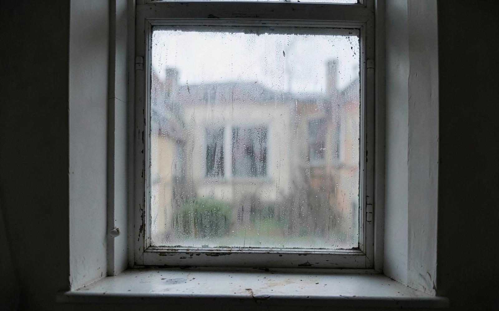 Old single-glazed window covered in condensation on a grey morning
